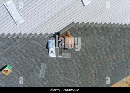 Construction worker uses an air hammer to nail wooden beams housing ...