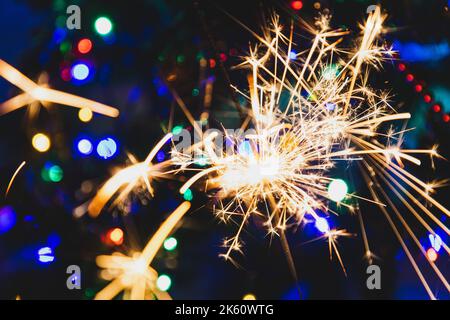 Burning sparkler, on the background of multi-colored bokeh. Stock Photo