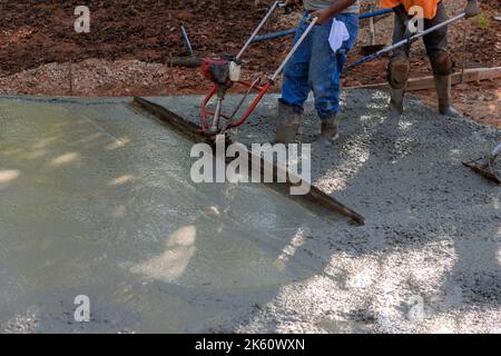 Machine to align fresh concrete compacted layer fresh concrete on new driveway construction. Stock Photo