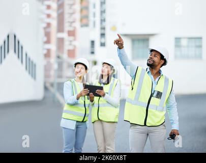 Construction, planning and architects talking about a building project together with a tablet. Team of engineer employees speaking about maintenance Stock Photo