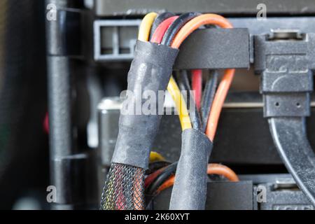 Very dirty wires with connectors are connected to the computer hard drive. HDD and SSD disc. Old colored wires in braided wrapper. Stranded electrical Stock Photo