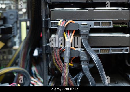 Very dirty wires with connectors are connected to the computer hard drive. HDD and SSD disc. Old colored wires in braided wrapper. Stranded electrical Stock Photo