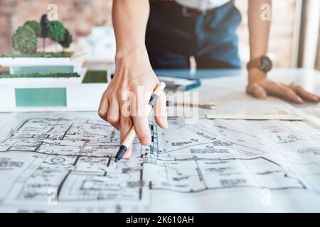 Closeup shot hand of a woman architect holding a pen and looking over plans, blueprints are schematics. One caucasian business woman brainstorming and Stock Photo