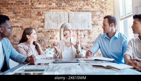Group of diverse architects discussing plans, blueprints and schematics during a meeting in their office boardroom. Business people brainstorming and Stock Photo