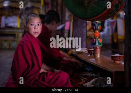 A young monk with a drum at Thikse Monastery (Gompa) during morning puja, Ladakh, India Stock Photo