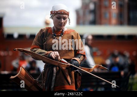 Medieval archery tournament. A woman shoots an arrow in the medieval castle yard. Woman in medieval dress with a wooden bow in her hands. historical Stock Photo