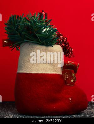 Christmas sock with a candle on it, a specific Christmas decoration. This image was taken on a red background Stock Photo