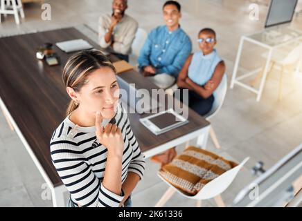 Group of diverse businesspeople having a meeting in an office at work. Young serious mixed race businesswoman thinking of an idea on a whiteboard in a Stock Photo