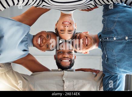 Portrait of a group of young diverse businesspeople smiling and huddling in support at work. Cheerful colleagues standing united to motivate each Stock Photo