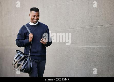 Businessman using his cellphone while walking in the city. Man using cellphone while commuting to work. Using internet while walking outside. Man Stock Photo