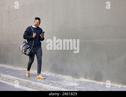 Businessman using his cellphone while walking in the city. Man using cellphone while commuting to work. Using internet while walking outside. Man Stock Photo