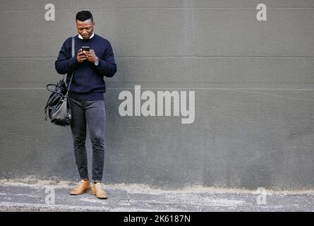 Businessman using his cellphone while walking in the city. Man using cellphone while commuting to work. Using internet while walking outside. Man Stock Photo