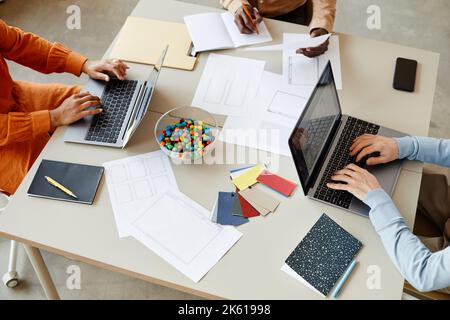 Top view closeup of creative team of three using laptops while working together at table, office collaboration background Stock Photo