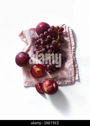 Fresh plums and grapes on white background. Purple food. Harvest concept. Stock Photo