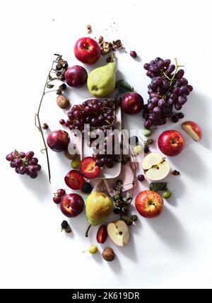 Composition with fresh summer fruits and berries on white background. Grapes, plums and apples in sunlight. Stock Photo