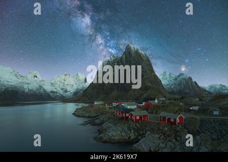 Spectacular scenery of glowing stars of Milky Way in night sky over over residential houses located in highlands near lake in Norway at night Stock Photo