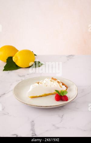 High angle of lemon meringue tart served on plate near ripe strawberries on marble table Stock Photo