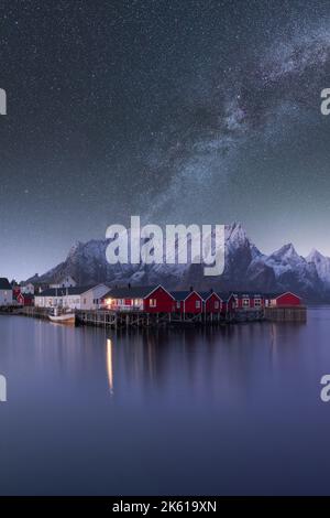 Spectacular scenery of glowing stars of Milky Way in night sky over over residential houses located in highlands near lake in Norway at night Stock Photo