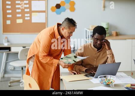 Portrait of black young woman consulting colleague on project developing while working together in meeting Stock Photo