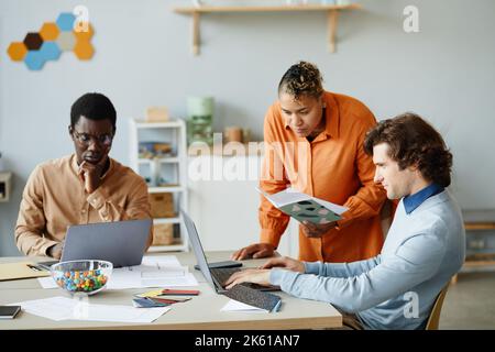 Portrait of diverse creative team collaborating in meeting and using laptops focus on black female manager talking to colleagues Stock Photo