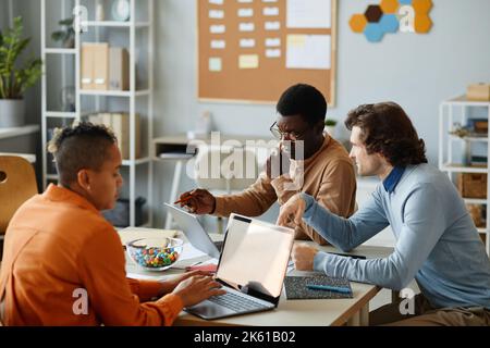 Portrait of busy business team using laptops while collaborating at meeting table in office Stock Photo