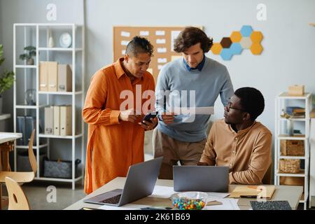 Creative business team of three working together in office and discussing project development Stock Photo