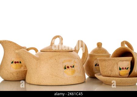 Two clay cups on a saucer, a milk jug, a teapot and a sugar bowl, macro, isolated on a white background. Stock Photo