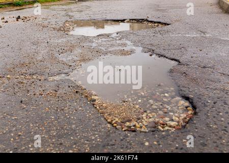 Water filled pot hole in the road. Copy space area for construction road repair designs and concepts Stock Photo