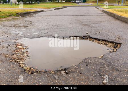 Water filled pot hole in the road. Copy space area for construction road repair designs and concepts Stock Photo