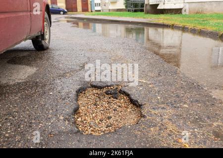 Water filled pot hole in the road. Copy space area for construction road repair designs and concepts Stock Photo