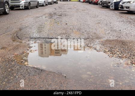 Water filled pot hole in the road. Copy space area for construction road repair designs and concepts Stock Photo