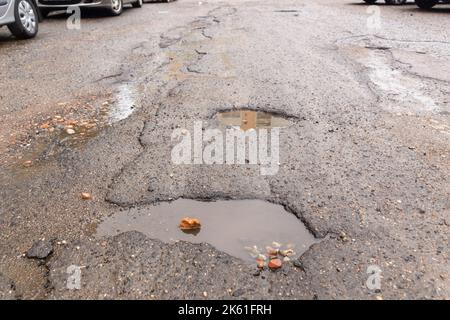 Water filled pot hole in the road. Copy space area for construction road repair designs and concepts Stock Photo