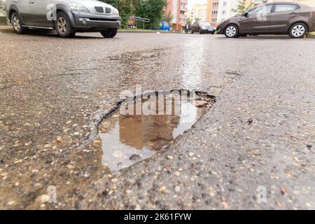 Water filled pot hole in the road. Copy space area for construction road repair designs and concepts Stock Photo