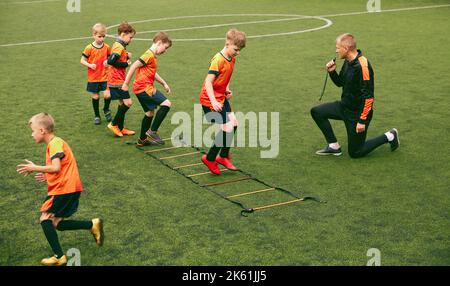 Workout. Junior soccer team training with football coach at sports stadium, outdoors. Concept of sport, competition, studying and achievements Stock Photo