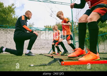 Workout. Junior soccer team training with football coach at sports stadium, outdoors. Concept of sport, competition, studying and achievements Stock Photo