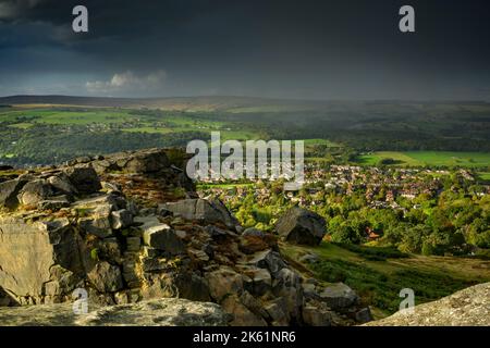 Cow & Calf Rocks overlooking scenic atmospheric rural landscape (high moorland hill crag, sun & raining) - Ilkley Moor, West Yorkshire, England, UK. Stock Photo