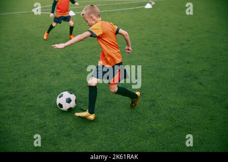 Workout. Junior soccer team playing football at sports stadium, outdoors. Concept of sport, competition, studying and achievements Stock Photo