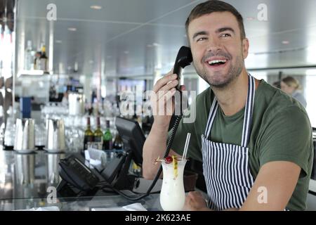 Restaurant worker taking a reservation on landline telephone Stock Photo