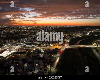 Light streaks from cars moving through busy intersection after sunset Stock Photo
