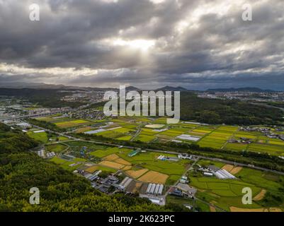 Sun shines through typhoon clouds over farmland in Japanese countryside Stock Photo