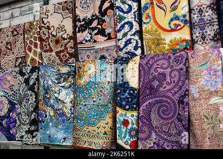 Multicolored patterned fabrics in a market. Full frame stacks of colored cloths. Colorful shawls in tourist shop in Turkey. Denizli, Turkey - Septembe Stock Photo