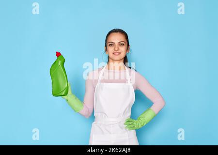 woman in gloves and cleaner apron holding bottle of detergent Stock Photo