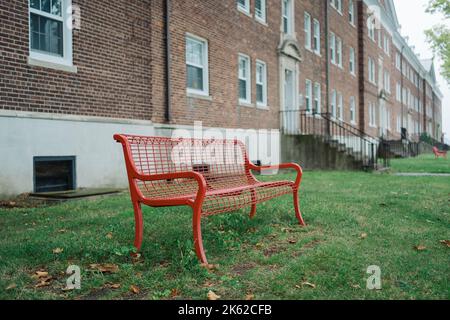 Red bench in front of brick building, Governors Island, Manhattan, New York Stock Photo