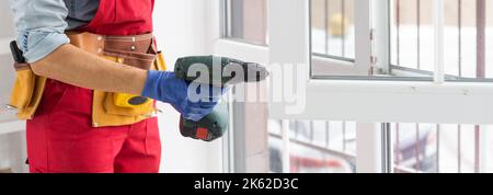 master with a screwdriver sets fittings on the window Stock Photo