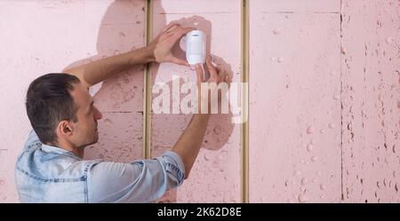 Electrician installing fire alarm on wall Stock Photo