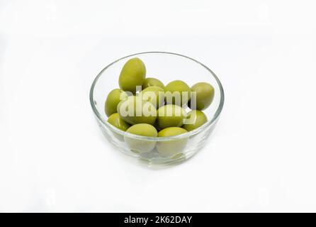 Whole green olives closeup in a clear glass bowl on white Stock Photo