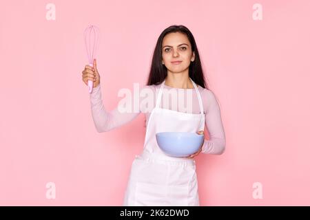 woman holding whisk and bowl with eggs Stock Photo