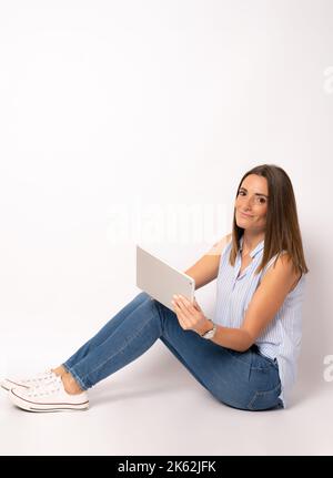 Young woman sitting on the floor using a digital tablet isolated over white background. Stock Photo