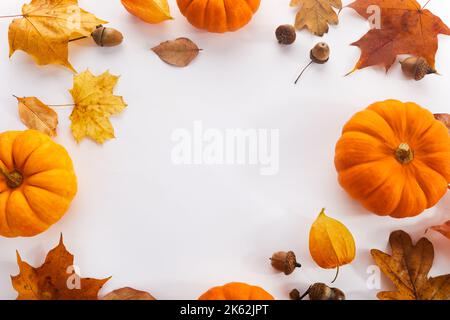 Pumpkins with fall leaves over white background. Top view. Stock Photo