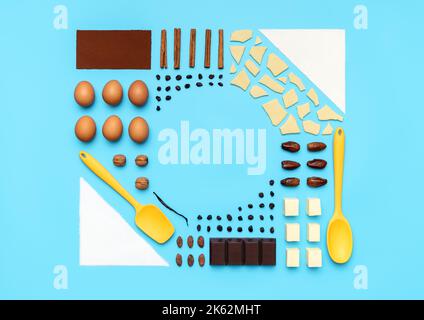 Top view with ingredients and utensils for baking arranged symmetrically on a blue table. Food knolling with ingredients for baking dessert. Stock Photo